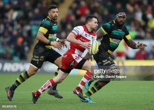 Tom Marshal of Gloucester runs with the ball watched by Api Ratuniyarawa and Luther Burrell during the Aviva Premiership match between Northampton...