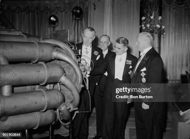 From left to right, Thomas Sopwith, engineer George Carter , Sir Frank Whittle and Sir Frank S. Spriggs examine a Whittle W1 jet engine during a...