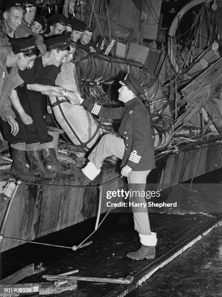 English writer, actor and director Noël Coward embarks on the 'HMS Torrin' during the filming of the naval drama 'In Which We Serve' at Denham...