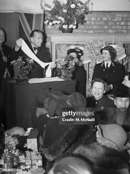 English writer, actor and director Noël Coward auctions a pair of stockings worn by Queen Victoria at Marylebone, London, 11th June 1941. The...
