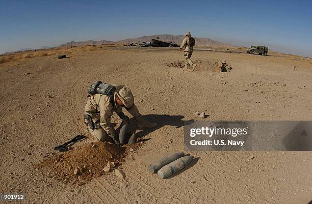 Navy Lt. Mike Runkle of Virginia Beach, Va., assigned to Explosive Ordnance Disposal, Mobile Unit Two, Detachment-18 prepares charges to blow up...