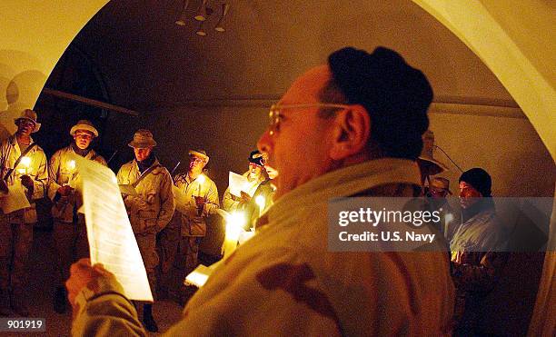 Navy Chaplain Cmdr. Joseph Scordo of Pleasantville, NY, leads Christmas carolers in celebrating the holiday season December 24, 2001 at a forward...