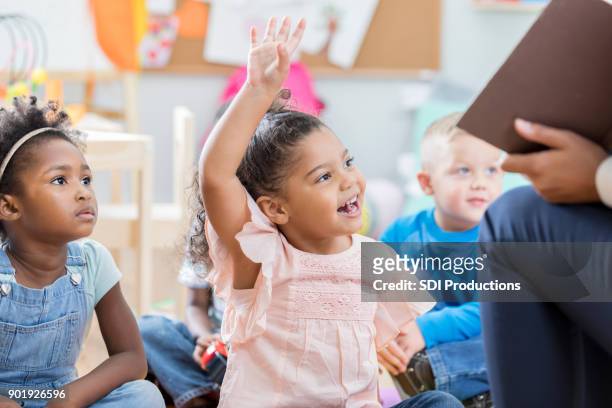 little girl raises hand during story time - asking time stock pictures, royalty-free photos & images
