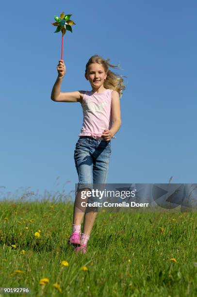 girl on meadow runing with a colorful pin windmill - adac stock pictures, royalty-free photos & images