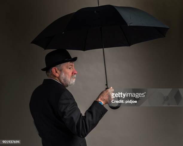 sad englishman with bowler hat, umbrella and newspaper under the arm, grey background"nbrexit concept: representing the choice in the british referendum on eu membership. - bowler hat stock pictures, royalty-free photos & images