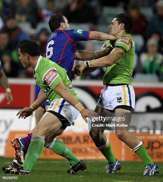 Ben Rogers of the Knights punches Daniel Vidot of the Raider during the round 25 NRL match between the Canberra Raiders and the Newcastle Knights at...