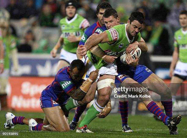 David Shillington of the Raiders is wrapped up by the Knights defence during the round 25 NRL match between the Canberra Raiders and the Newcastle...