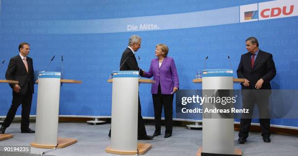 German Chancellor Angela Merkel shakes hands with Saxony's Governor Stanislaw Tillich as Dieter Althaus , governor of the eastern German state of...