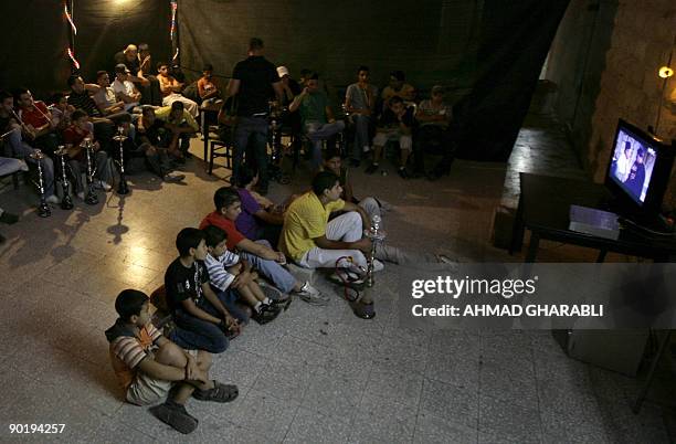 Palestinian men and children watch an episode of the Syrian TV drama series "Bab al-Hara" at a cafe in Arab east Jerusalem, after breaking their fast...