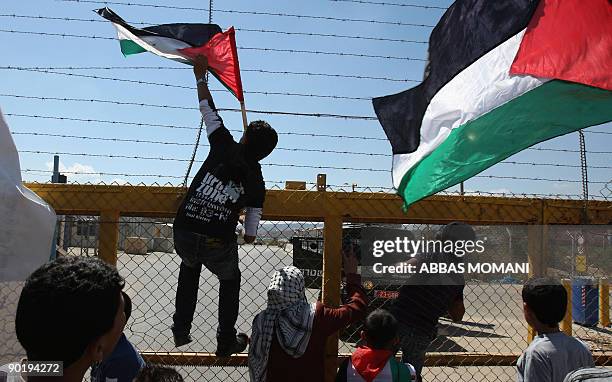 Palestinians wave their national flag at the gate of the Israeli controlled Ofer jail during a protest calling for the release of prisoners on August...