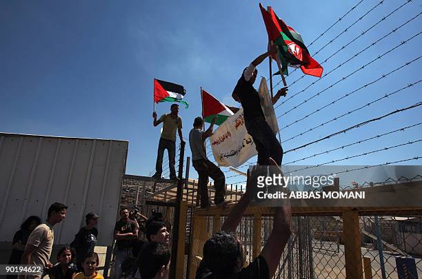 Palestinians wave their national flag as they climb up the gate of the Israeli controlled Ofer jail during a protest calling for the release of...