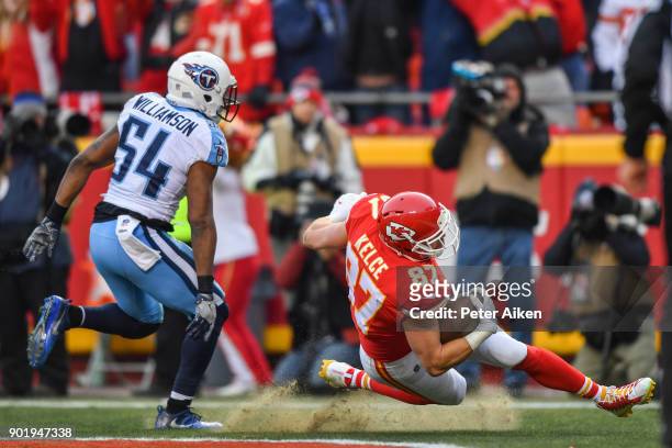 Tight end Travis Kelce of the Kansas City Chiefs loses his footing while making a touchdown catch in front of inside linebacker Avery Williamson of...