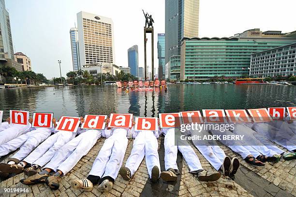 Activists from Oxfam, the WWF, and Greepeace stage a joint protest in front of cut-outs featuring the faces of heads of states of G8 countries and...