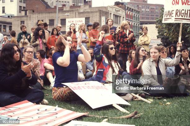 Young men and women sit and gather at a park while holding a sign that reads 'Our Right To Decide' at a reproductive rights demonstration,...