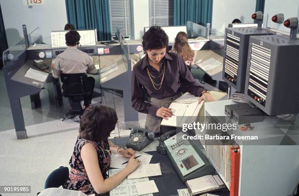 Two women discuss a report while working in a computer-equipped office, Pittsburgh, PA, ca. 1974.