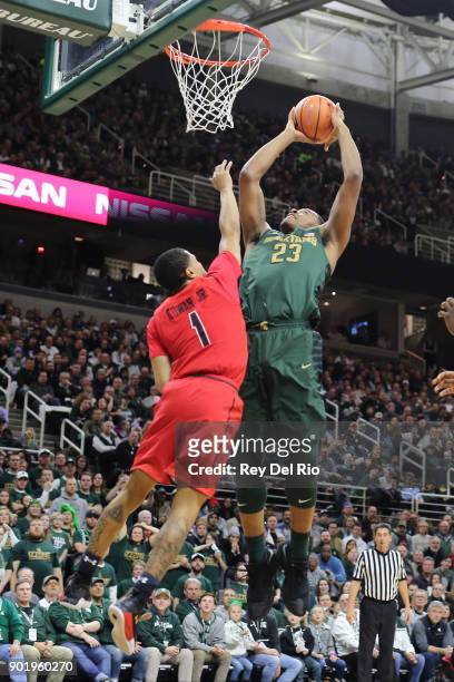 Xavier Tilman of the Michigan State Spartans shoots over Anthony Cowan Jr. #1 of the Maryland Terrapins at Breslin Center on January 4, 2018 in East...