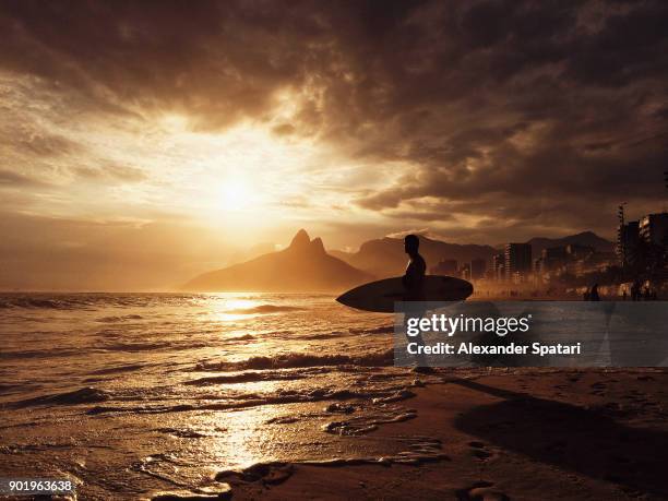 surfer waiting for a wave during sunset at ipanema beach, rio de janeiro, brazil - ipanema beach imagens e fotografias de stock