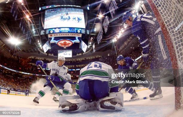 Jacob Markstrom of the Vancouver Canucks covers the puck as Matt Martin and Connor Brown of the Toronto Maple Leafs wait for the rebound and Derrick...