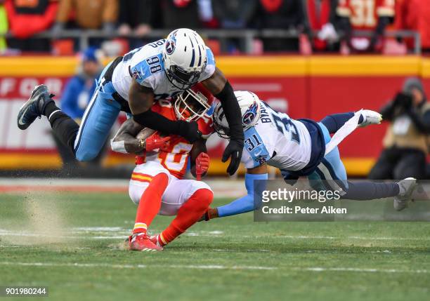 Wide receiver Tyreek Hill of the Kansas City Chiefs is tackled by outside linebacker Brian Orakpo and free safety Kevin Byard of the Tennessee Titans...
