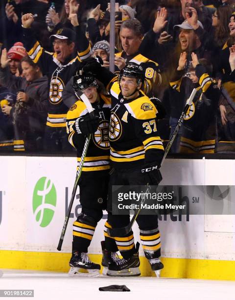 Patrice Bergeron of the Boston Bruins celebrates with Torey Krug after scoring his third goal against the Carolina Hurricanes at TD Garden on January...