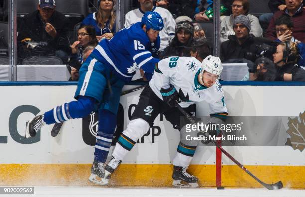 Mikkel Boedker of the San Jose Sharks and Matt Martin of the Toronto Maple Leafs battle for the puck during the second period at the Air Canada...