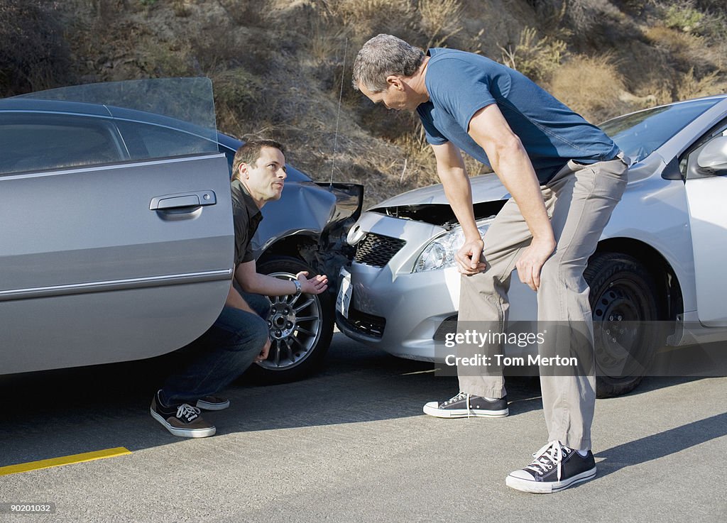 Two men examining damage in car collision