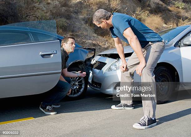 two men examining damage in car collision - unfall auto stock-fotos und bilder