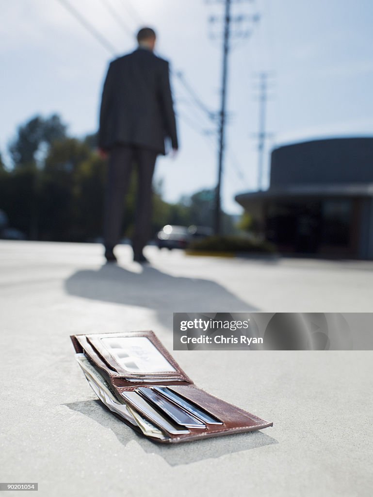 Businessman dropping wallet on sidewalk