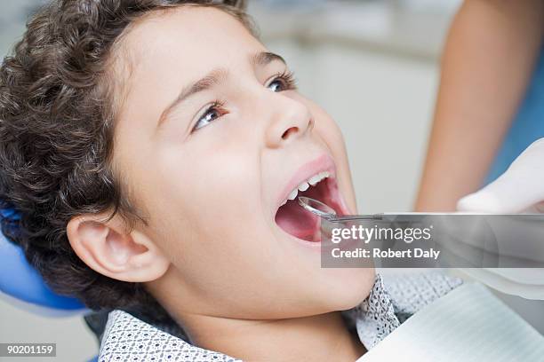 ragazzo avendo i suoi denti esaminato dal dentista - dentista bambini foto e immagini stock