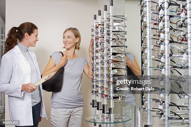 woman trying on glasses in optometrists shop - white coat fashion item stock pictures, royalty-free photos & images