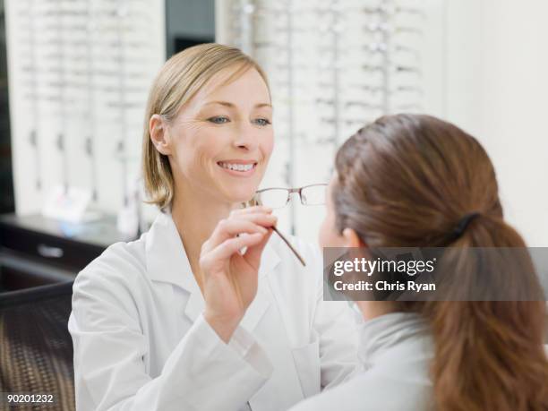 donna cercando su occhiali in negozio optometristi - optometria foto e immagini stock