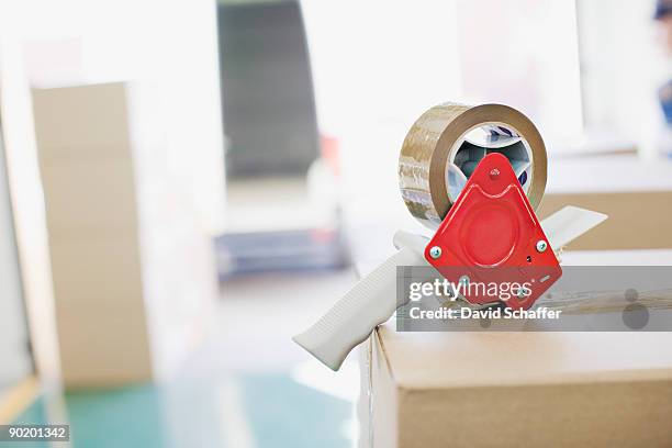 close up of tape dispenser on cardboard box - klebeband stock-fotos und bilder