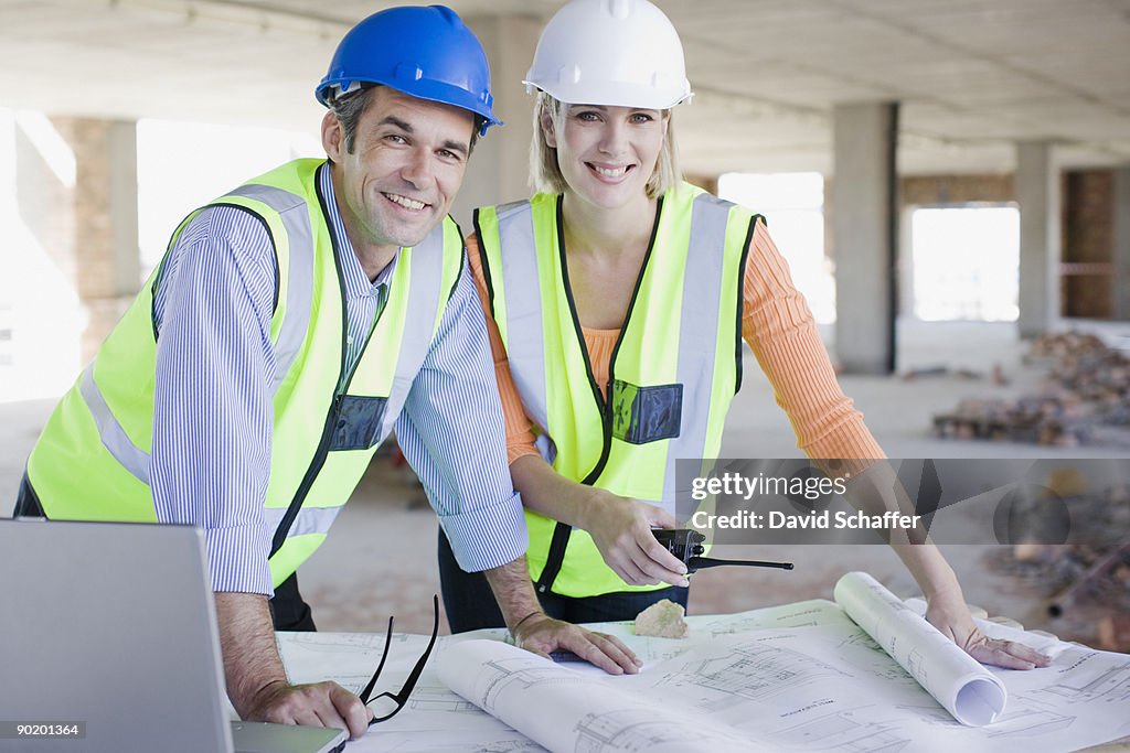 Co-workers working with blueprints on construction site