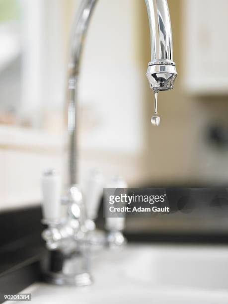 close up of water droplet dripping from kitchen faucet - haushaltsarmatur stock-fotos und bilder
