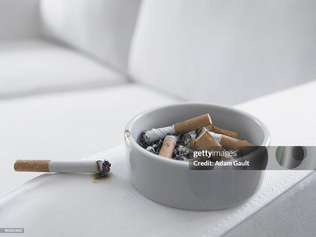 Cigarette burning arm of sofa