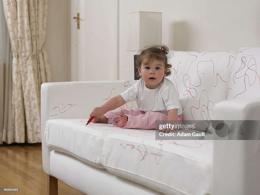 Baby girl using marker on sofa