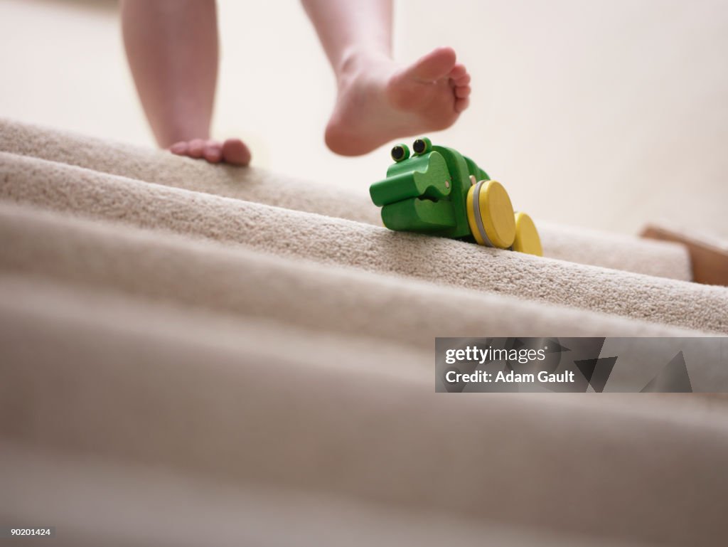 Woman about to slip on toy left on staircase