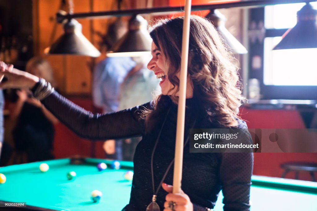 Happy hour for friends and coworkers in a bar playing pool.