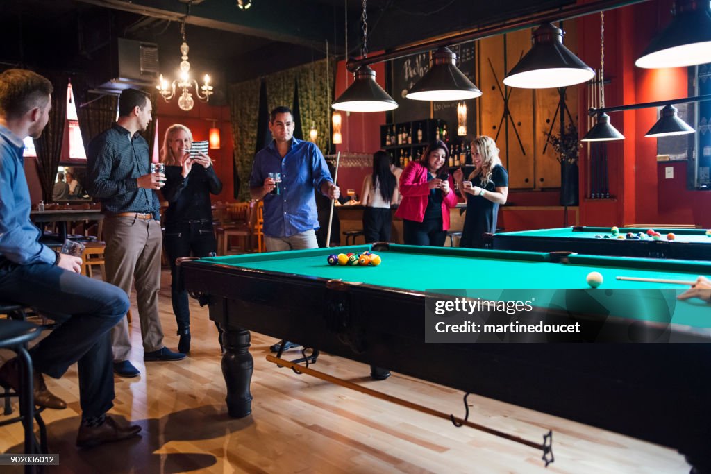 Happy hour for friends and coworkers in a bar playing pool.