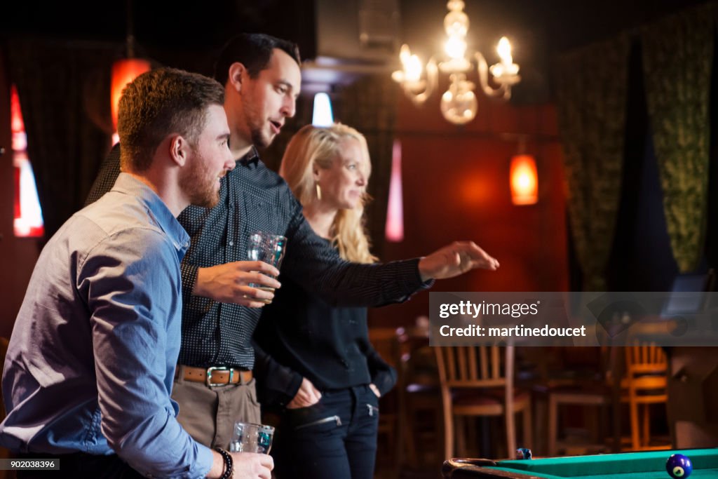 Happy hour for friends and coworkers in a bar playing pool.