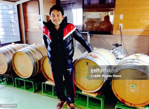 Takuma Inagawa, president of Japanese brewery venture Wakaze Inc. In Tsuruoka, Yamagata Prefecture, poses in front of oak wine barrels used to mature...