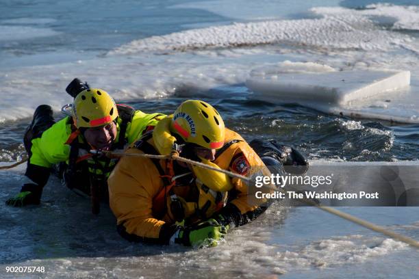 Mike Kriskovich practices rescuing fellow firefighter Matt Jackson during the Arlington Swift Water Rescue Team's ice rescue practice in an inlet...