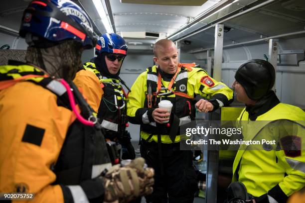 The Arlington Swift Water Rescue Team warms up inside the Arlington County Fire Department's Medical Ambulance Bus after practicing live ice rescues...