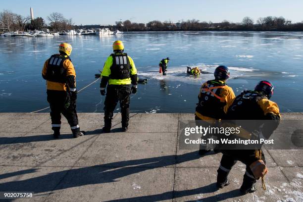 Jake Daniel, second from the right, and Josh Wise, right, of the Arlington Swift Water Rescue Team practice live ice rescues by pulling fellow...