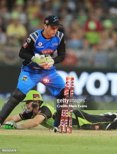 Ben Rohrer of Thunder slides into the crease as Alex Carey of the Strikers knocks the bails off during the Big Bash League match between the Sydney...