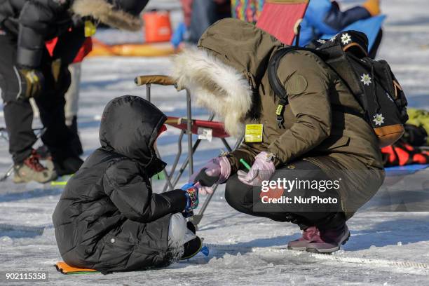 Visitors cast lines through holes drilled in the surface of a frozen river during a trout catching contest in Hwacheon, South Korea on 6 January...