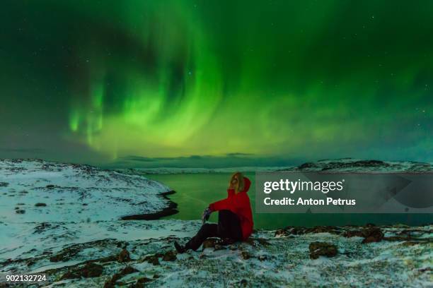 man in a red jacket on a background of the northern lights - northern lights iceland stockfoto's en -beelden