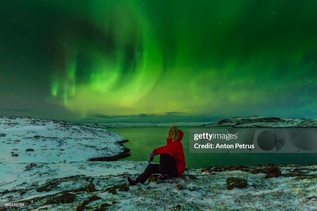 Man in a red jacket on a background of the Northern Lights
