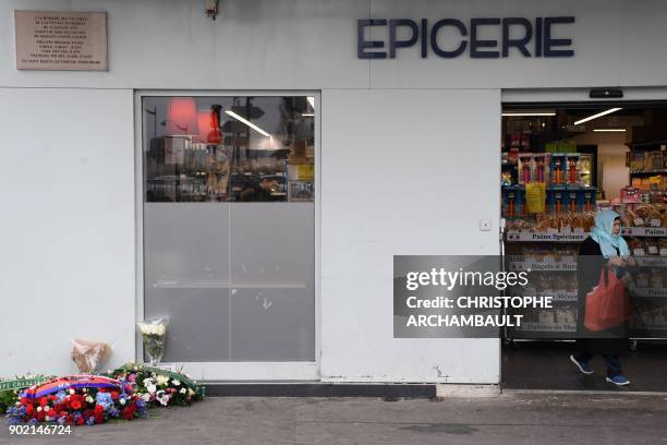 Wreaths have been placed under a commemorative plaque as a woman leaves the Hypercacher market in Porte de Vincenne in eastern Paris on January 7...