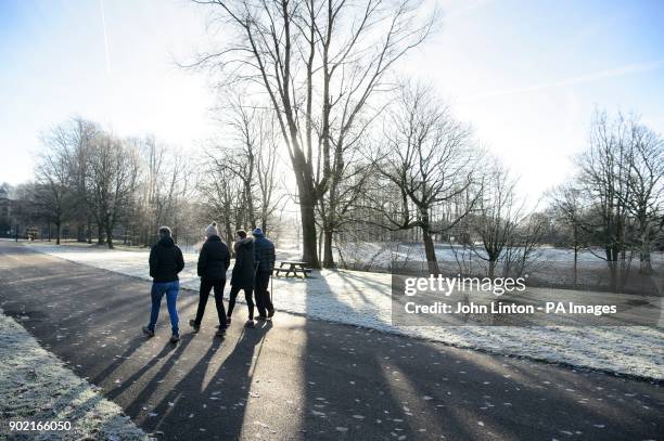 People stroll in widespread frost in Glasgow's Pollok Park, as temperatures plummet across the UK.